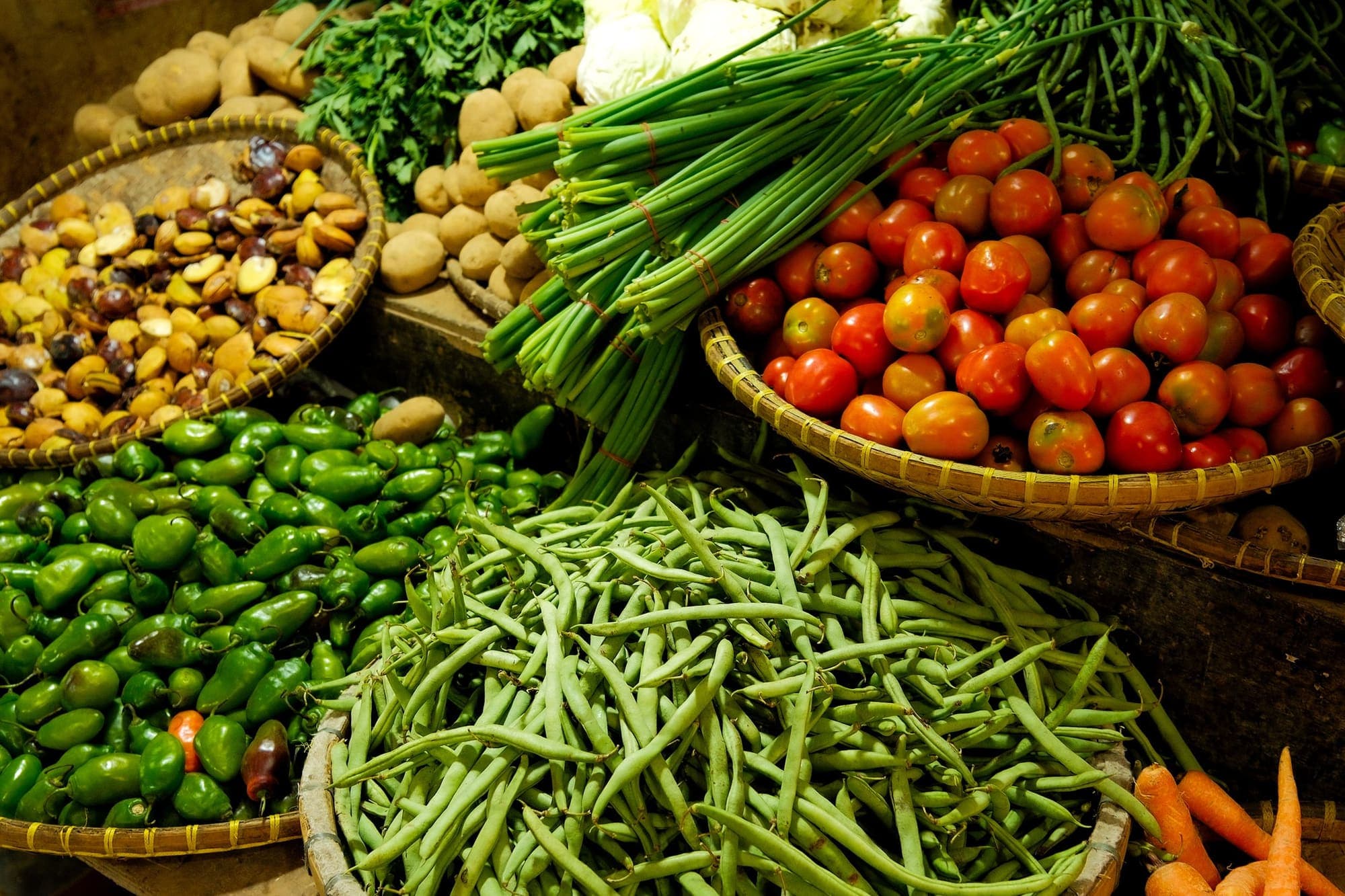 Baskets of beans, tomatoes and greens at a market