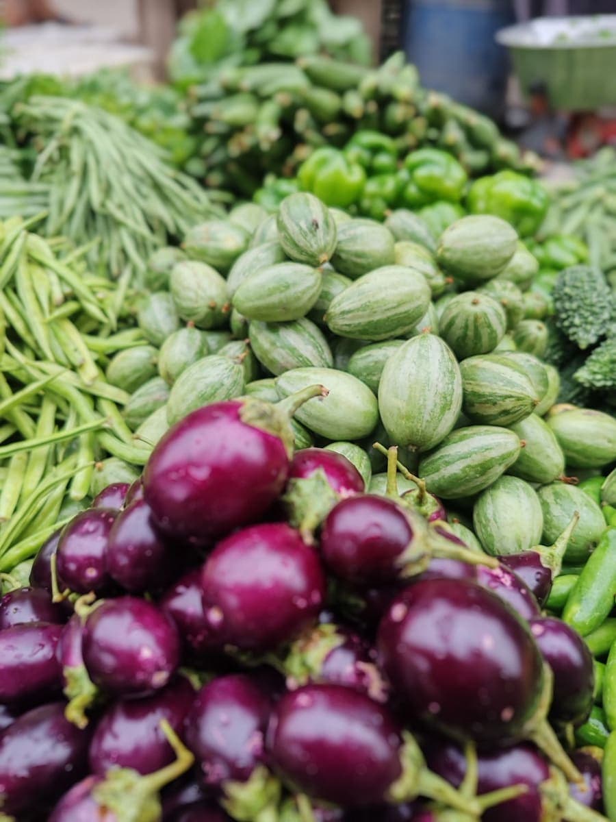Purple brinjals and green beans piled at a stall