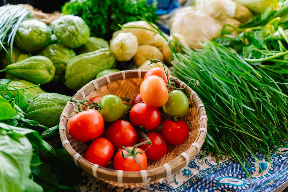 A basket of tomatoes surrounded by fresh greens at a market